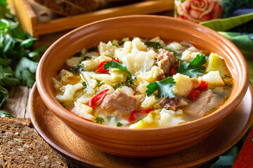 Traditional Hungarian thick soup with beef, vegetables and dumplings on a wooden table. Hot dinner or lunch.