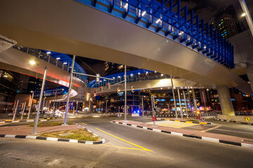 Night view of an oversized pedestrian bridge across a major road in the Dubai Marina district, Dubai, UAE, surrounded by skyscrapers