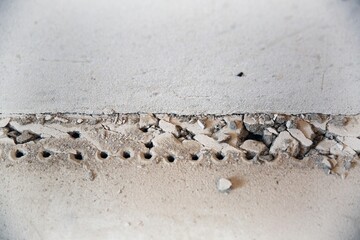 Stones on the floor, broken floor, devastation, screed, flooring repair. Concrete wall in the room. Cement. Renovation in a new building. Bare walls. Plastering works.