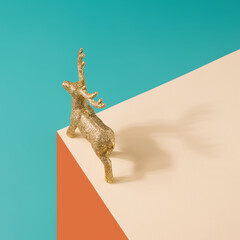 Fototapeta premium Golden reindeer figurine on a pastel surreal background. Christmas minimal concept. 