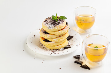 curd cakes, curds on a white dessert plate with chocolate and mint, green tea in glass cups