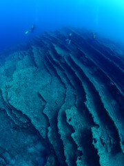 scuba divers exploring underwater topography of strange rocks and reef