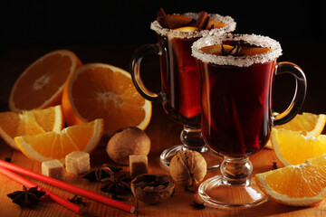 Two cups with ready mulled wine with anise, cinnamon and nuts around