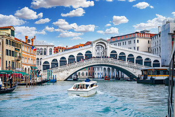 Venezia, Italia. Vista del Ponte di Rialto su Canal Grande da un vaporetto.  Si intravede la fermata Rialto del battello e alcune barche. - obrazy, fototapety, plakaty