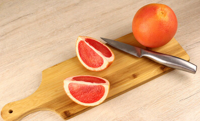 Grapefruit on a wooden cutting board with a metal knife