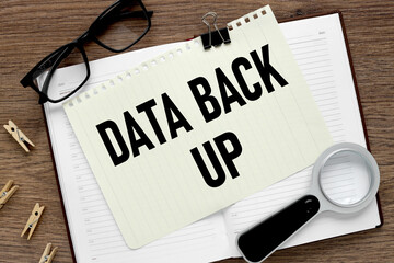Data Back up. text on a white paper notebook on a wooden background.