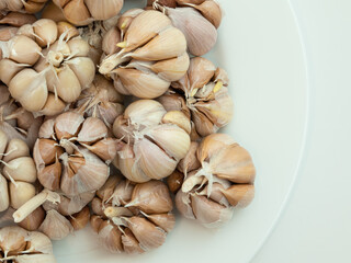 A lot of whole garlic peeled off to cloves on white plate and isolated on white background. Close up, top view.