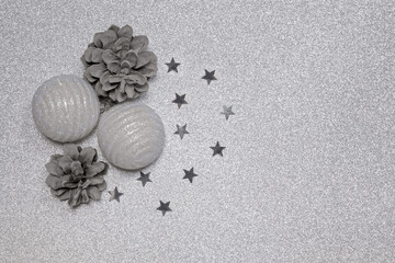 Gray Pine Cones, White Baubles and Metallic Star-shaped Confetti. Christmas Tree Decoration on a White Glitter Background ideal for Card, Banner, Newsletter.