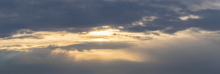 Dark stormy sky during sunset, the sun's rays penetrate the dark clouds