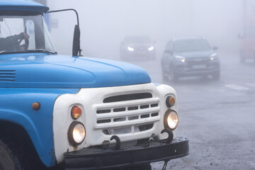 Fog on the road. An old truck drives into a city crossroads.