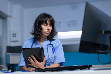 Medical assistant using tablet with touch screen for healthcare system. Nurse holding digital...