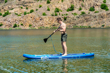 Sporty man on sup board with paddle in the lake