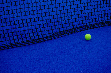 Pista de paddle tennis. Una pelota aislada cerca de la red.