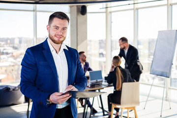 Successful handsome male mentor, director, businessman in a suit at the office. Working day concept. Team meeting with the boss in the foreground