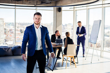 Successful handsome male mentor, director, businessman in a suit at the office. Working day concept. Team meeting with the boss in the foreground