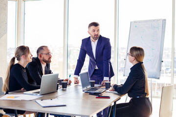 Business people working together in a modern office with cityscape view. The director tells the staff about new technologies. Office work concept