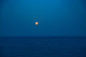 Full Red Moon Glows Brightly in the Blue Sky on a Evening Over the Sea