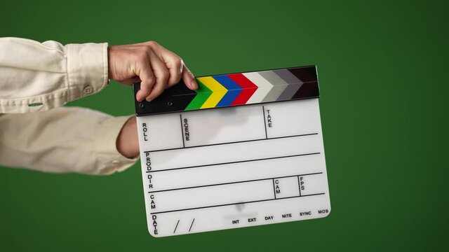 Man holding large video cinema clapper board and opening and clapping it shut on a green screen chroma key background.