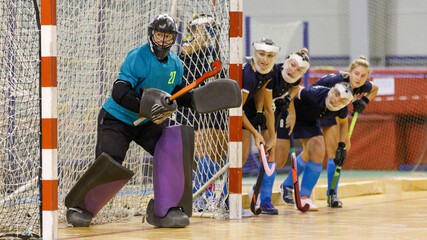 Goalkeeper and her teammates defence the net from the corner shot in indoor hockey game.