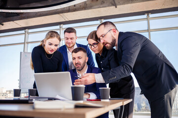 Business, technology and office concept - happy business team with laptop computers, documents and coffee. Meeting before the start of the working day to discuss a business plan