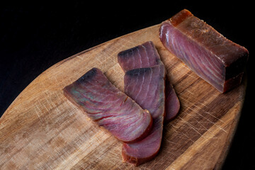Several pieces of tuna jerky (mojama) on a plate accompanied by salted almonds. - obrazy, fototapety, plakaty