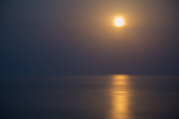 The Full Red Moon Shines Brightly in the Sky on a Dark Night Over the Calm Sea. Beautiful Moon Path...