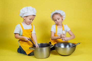 kids in apron and chef's hat sitting on the floor with a bowl and whisk