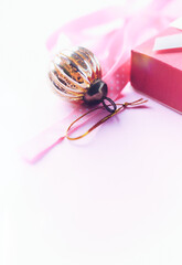 Christmas golden bauble on bright paper background. Close up. Copy space. 