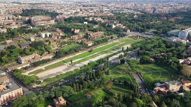 Aerial drone video of iconic Circus Maximus a green space and remains of a stone - marble arena used for chariot races built next to Palatine hill and world famous Colosseum, historic Rome, Italy