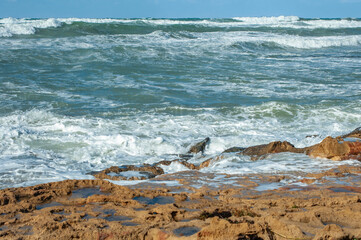 Fototapeta na wymiar A strong November wind drives roaring waves to the shore, tearing white foam from them. All the beaches of Paphos and nearby villages are flooded with stormy waters. 