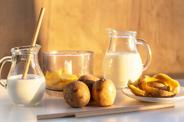Vegan plant milk from potato in glass jar and potato tubers on the table. Concept of potato milk, vegan sustainable option, plant-based dairy. Substitute drink, healthy eating, diet, nutrition