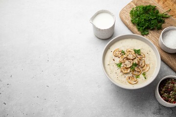 Bowl with mushroom cream soup, parsley, salt and croutons, toast on grey table. Champignon soup. Top view. copy space.