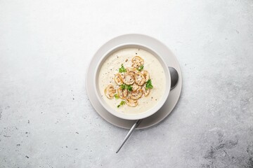 Bowl with mushroom champignon cream soup on grey table. Top view, copy space.