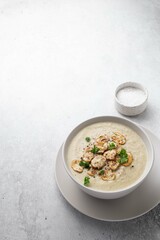 Bowl with mushroom champignon cream soup and salt on grey table. Top view, copy space.