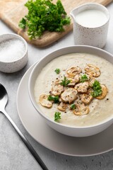 Bowl with mushroom cream soup, parsley and salt on grey table. Champignon soup.
