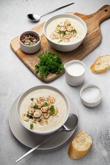 Bowl with mushroom cream soup, parsley, salt and croutons, toast on grey table. Champignon soup.