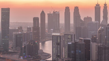 Obraz premium Skyline with modern architecture of Dubai business bay towers day to night timelapse. Aerial view