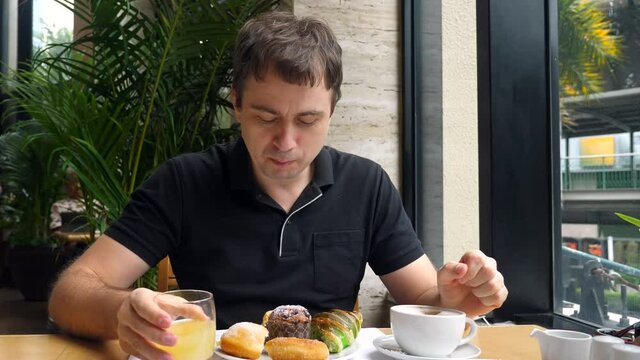 Portrait Of Smiling Man Drinking Coffee And Pineapple Juice, Eating Breakfast With Fresh Bakery In Urban City Cafe. Morning Food In Modern Restaurant. Male On Holidays In Luxury Hotel