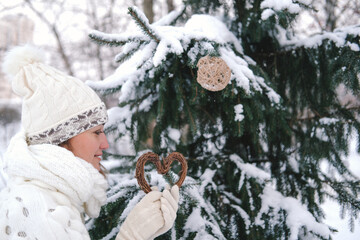 The girl decorates the Christmas tree with toys in the winter forest or park. Concept - Christmas vacations and holidays.