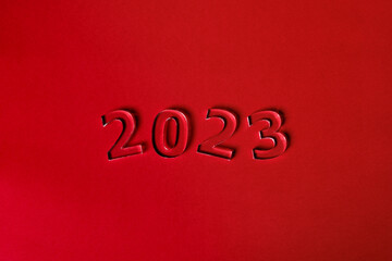 Fototapeta na wymiar Photo of numbers 2023 made of thick clear acrylic glass on a red background. View from above.