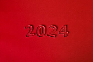 Fototapeta na wymiar Photo of numbers 2024 made of thick clear acrylic glass on a red background. View from above.