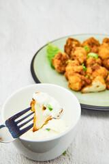 Vegan cauliflower buffalo wings on a fork. Tasty vegetarian food close up. crispy fried cauliflower bites