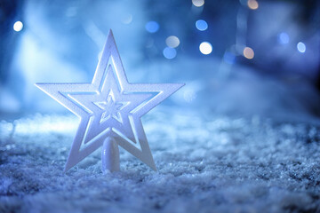 Christmas tree top star with snow and light lamps in rich bokeh