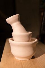 There are many rustic clay bowls on a wooden stand. Untreated ceramic products without glaze, view. Crafts, hobbies and lifestyle