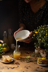 Home made limoncello liquer with honey,lemons and limes in glasswares on wooden background.Italian...