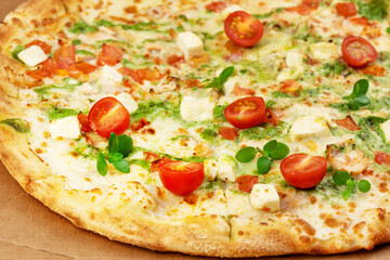 Natural italian big pesto pizza with thin dough, chicken, mozzarella, cherry tomatoes, bazil and pesto sauce on craft background, close up. Mediterranean cuisine. Healthy and testy fast food