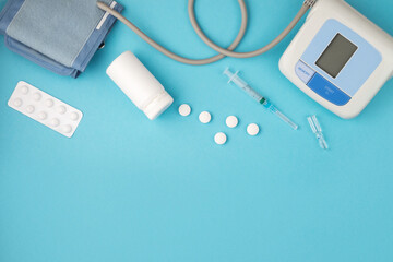 Medical concept, flat, lying on a blue background. Space for copying. Tonometer, pills, syringe on...