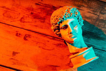 Gypsum copy of ancient statue Hermes head in orange turquoise neon light. Ancient greek sculpture...