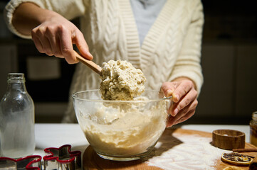 Female pastry chef kneads dough to make gingerbread for Christmas, in a cozy home atmosphere in the kitchen. Concept of delicious homemade sweet cookies