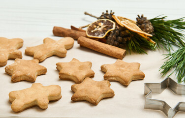 Gingerbread cookies as stars shape for Christmas, on a wooden surface with pine cones and branches, dried slices of orange and cinnamon sticks